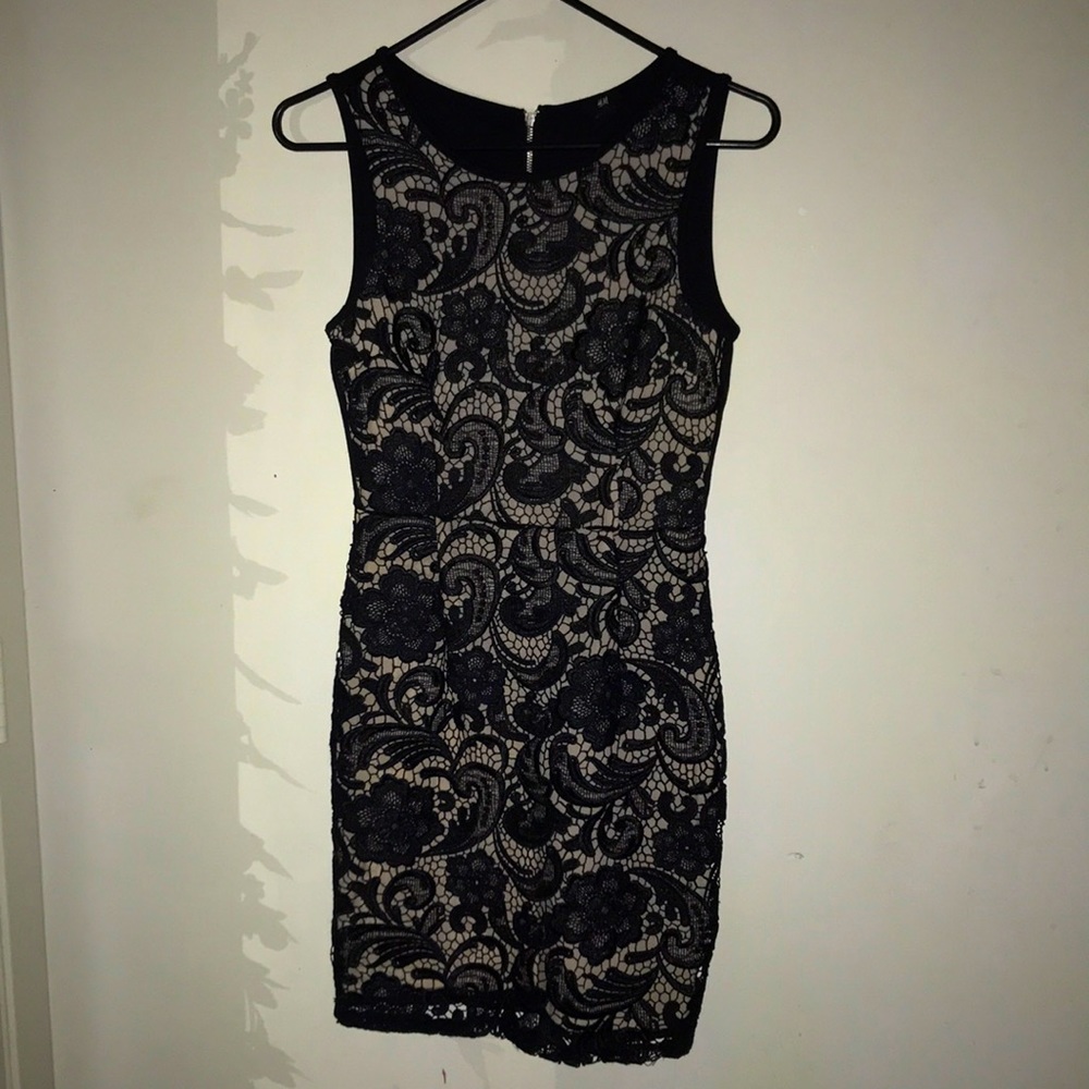 Nude background with a black floral pattern on top of it.